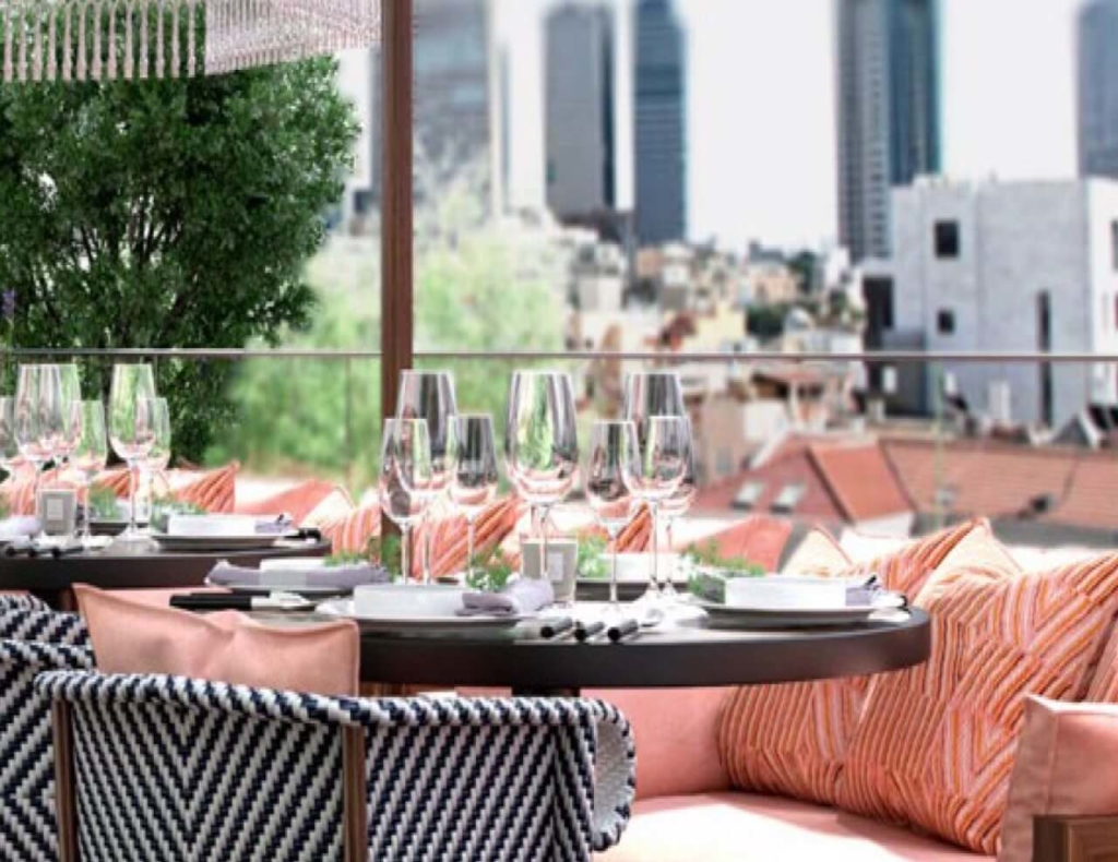 a dining table at the Deck health bar near the outdoor, decorated pool of the George Tel Aviv